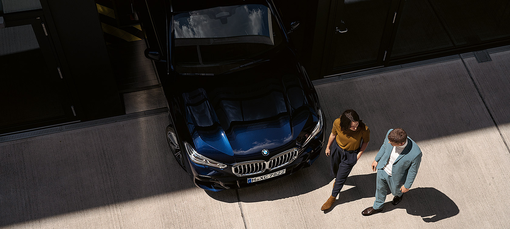 Moteris ir vyras einantys pro BMW vaizdas iš paukščio skrydžio