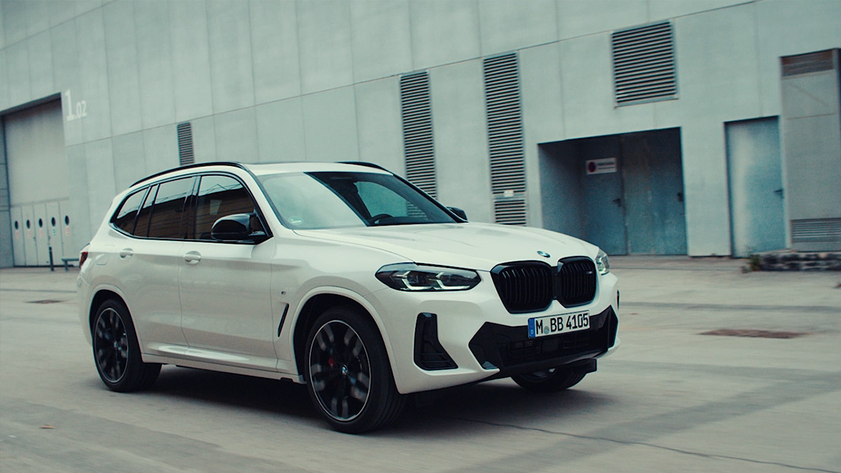 Pramoninių pastatų fone važiuojantis BMW automobilio grąžinimas BMW grąžinimas baltos spalvos BMW trijų ketvirčių vaizdas iš priekio pramoninių pastatų fone