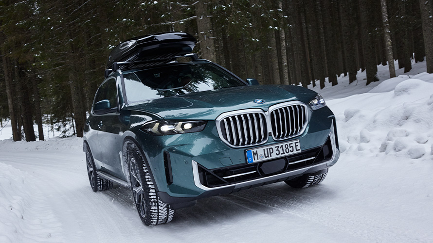 BMW žieminių ratlankių komplektas ant BMW X5 (G05 LCI) snieguotame miško kelyje BMW žieminių ratlankių komplektas ant BMW X5 (G05 LCI) snieguotame miško kelyje