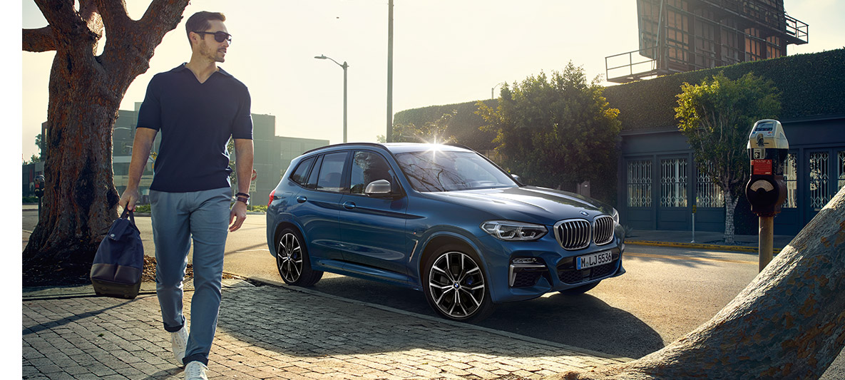 Vyras su akiniais nuo saulės priešais mėlyną BMW Vyras su akiniais nuo saulės priešais mėlyną BMW