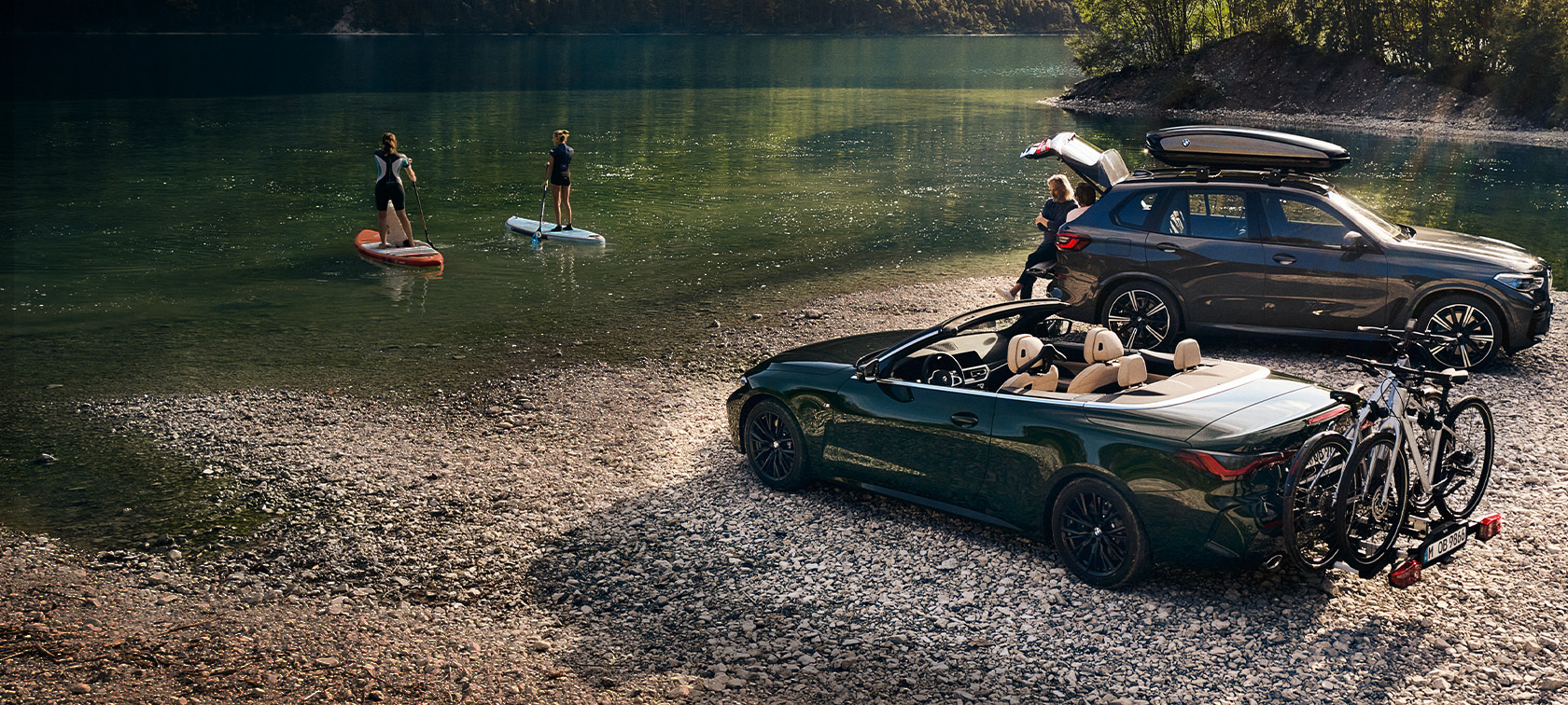 BMW automobiliai ežero ir kalnų kraštovaizdžio fone Pavasario ir vasaros sezonui skirti BMW aksesuarai BMW automobiliai ežero ir kalnų kraštovaizdžio fone