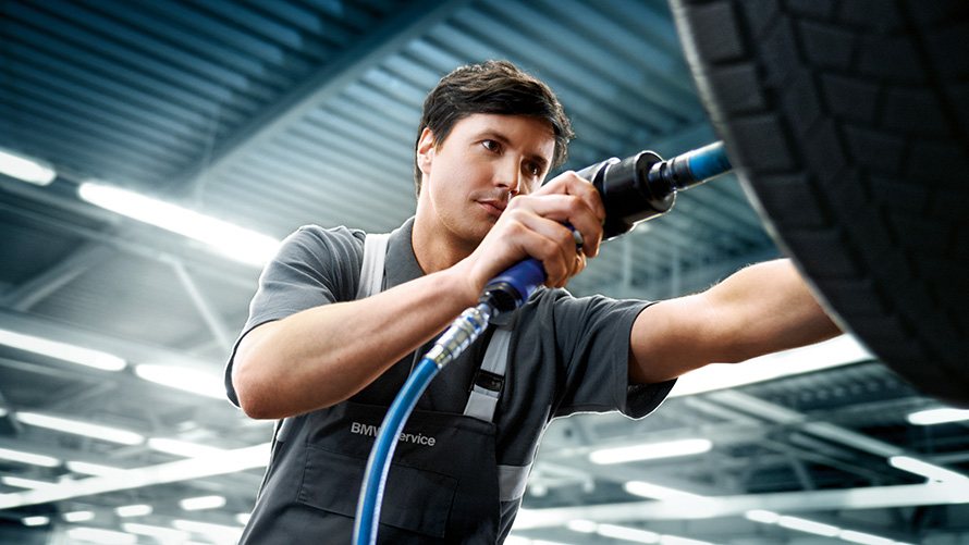 BMW pasiūlymai ratlankių servisas BMW vasaros pasiūlymai ratlankių servisas BMW serviso darbuotojas, remontuojantis BMW
