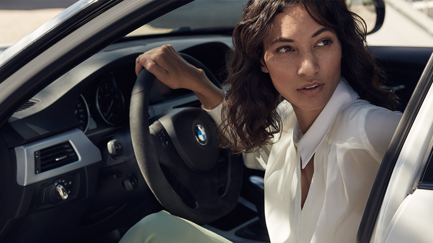 BMW Value Service BMW serviso klientė žiūri pro atviras savo BMW dureles