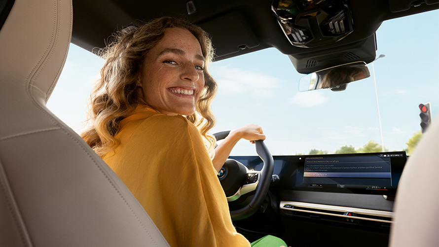 Paslaugos Proactive Care funkcionalumas, Proactive Care, patikra ir techninė priežiūra Iniciatyviosios priežiūros paslaugos Proactive Care funkcionalumas, Proactive Care, patikra ir techninė priežiūra, BMW automobilyje sėdinti ir ranką ant vairo laikanti moteris