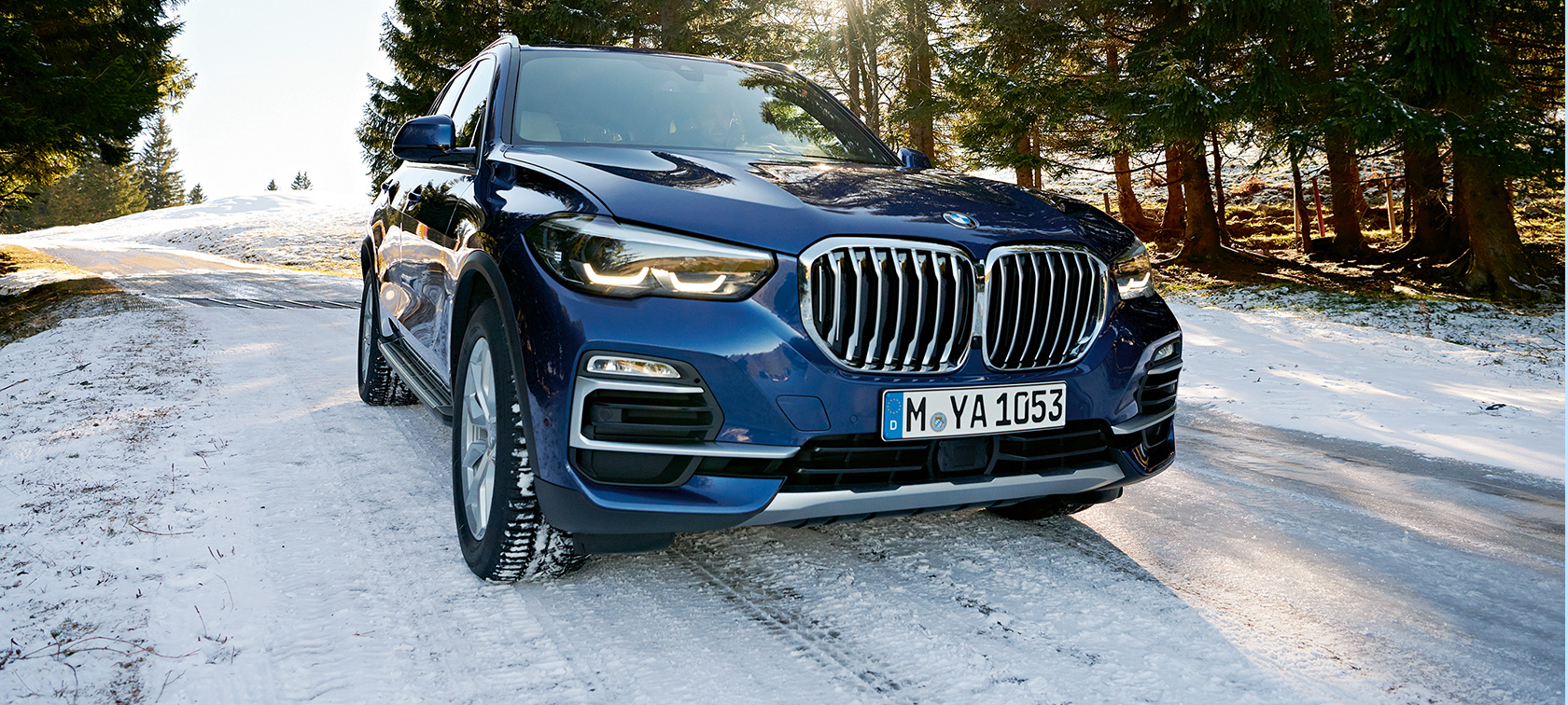 BMW rudens ir žiemos priedai Mėlynas BMW X3 snieguotame kelyje, trijų ketvirčių vaizdas iš priekio