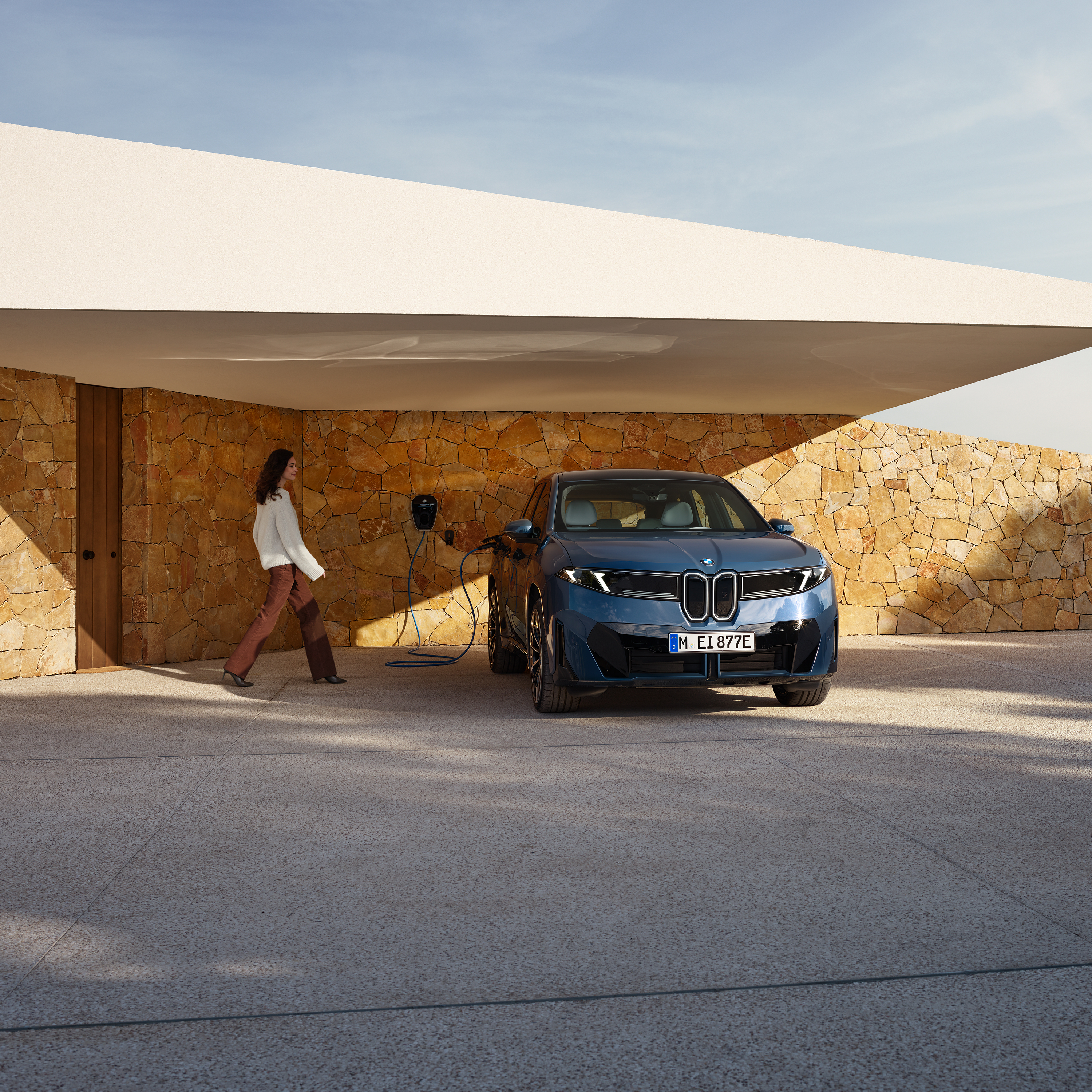 Moteris eina link sieninėje įkrovimo stotelėje įkraunamo BMW iX3