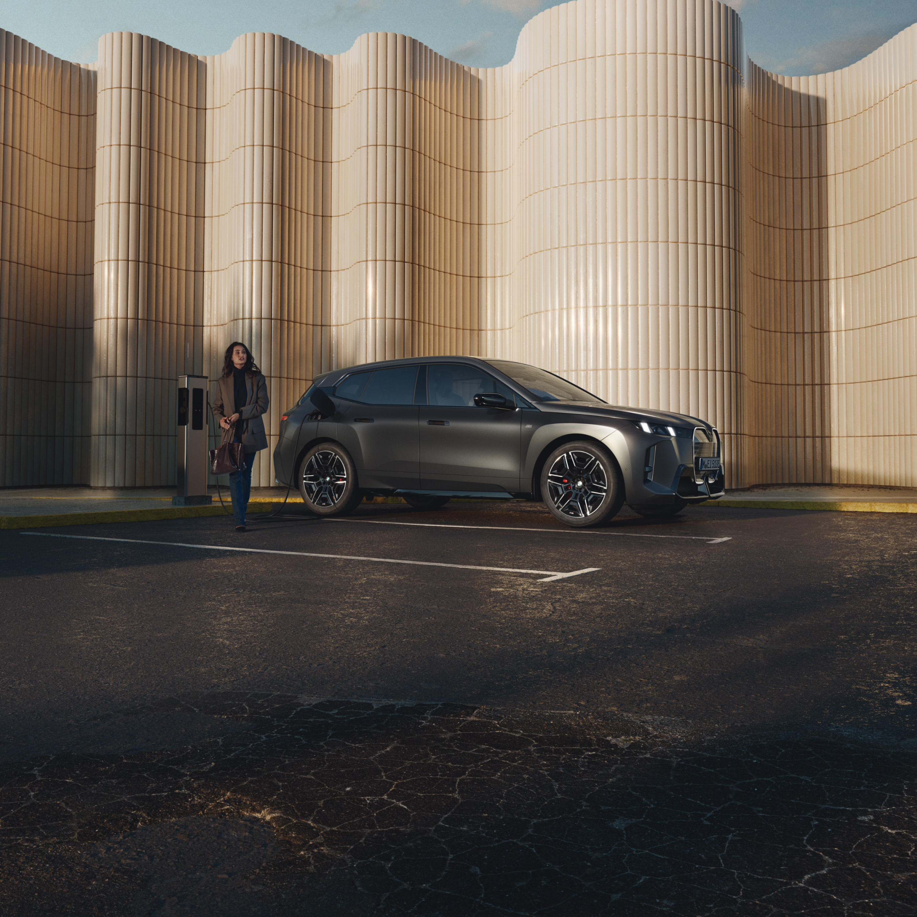 Į viešojo įkrovimo stotelėje  įkraunamą BMW atsirėmęs žmogus kelio pakraštyje